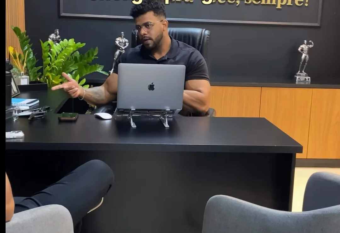 Dr. Dourado atendendo em seu consultório, sentado à mesa com o notebook