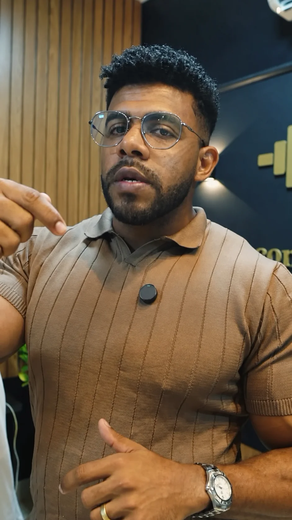Dr. Dourado de óculos e camisa polo falando para a câmera no consultório