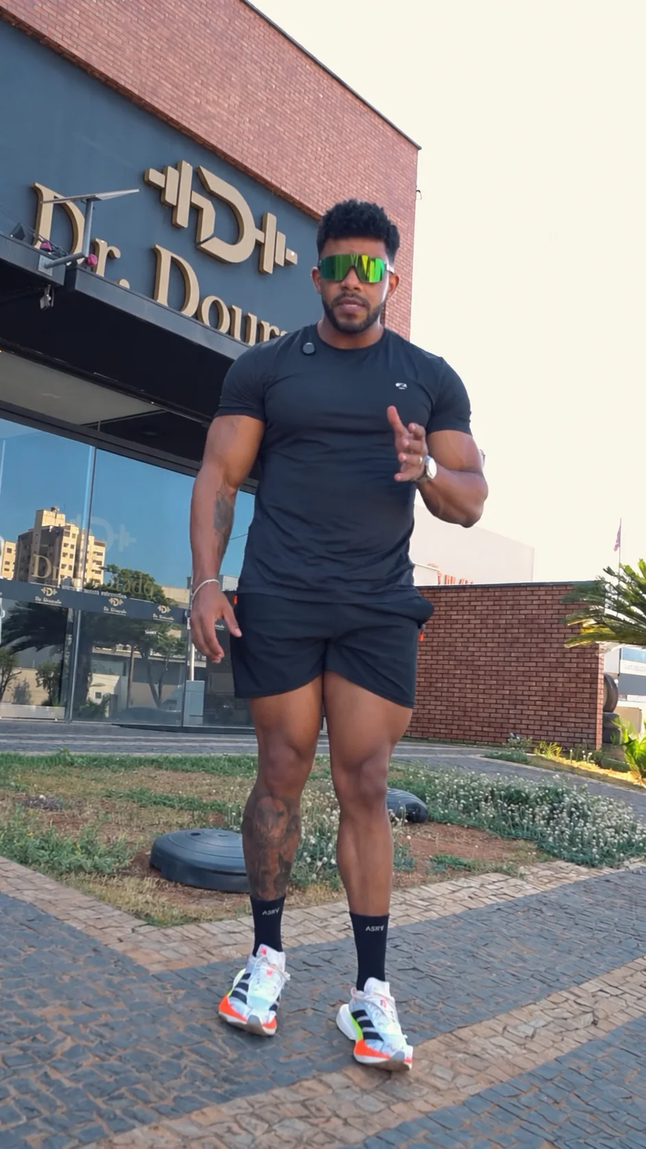 Dr. Dourado em roupa de treino diante da fachada da clínica com o nome Dr. Dourado